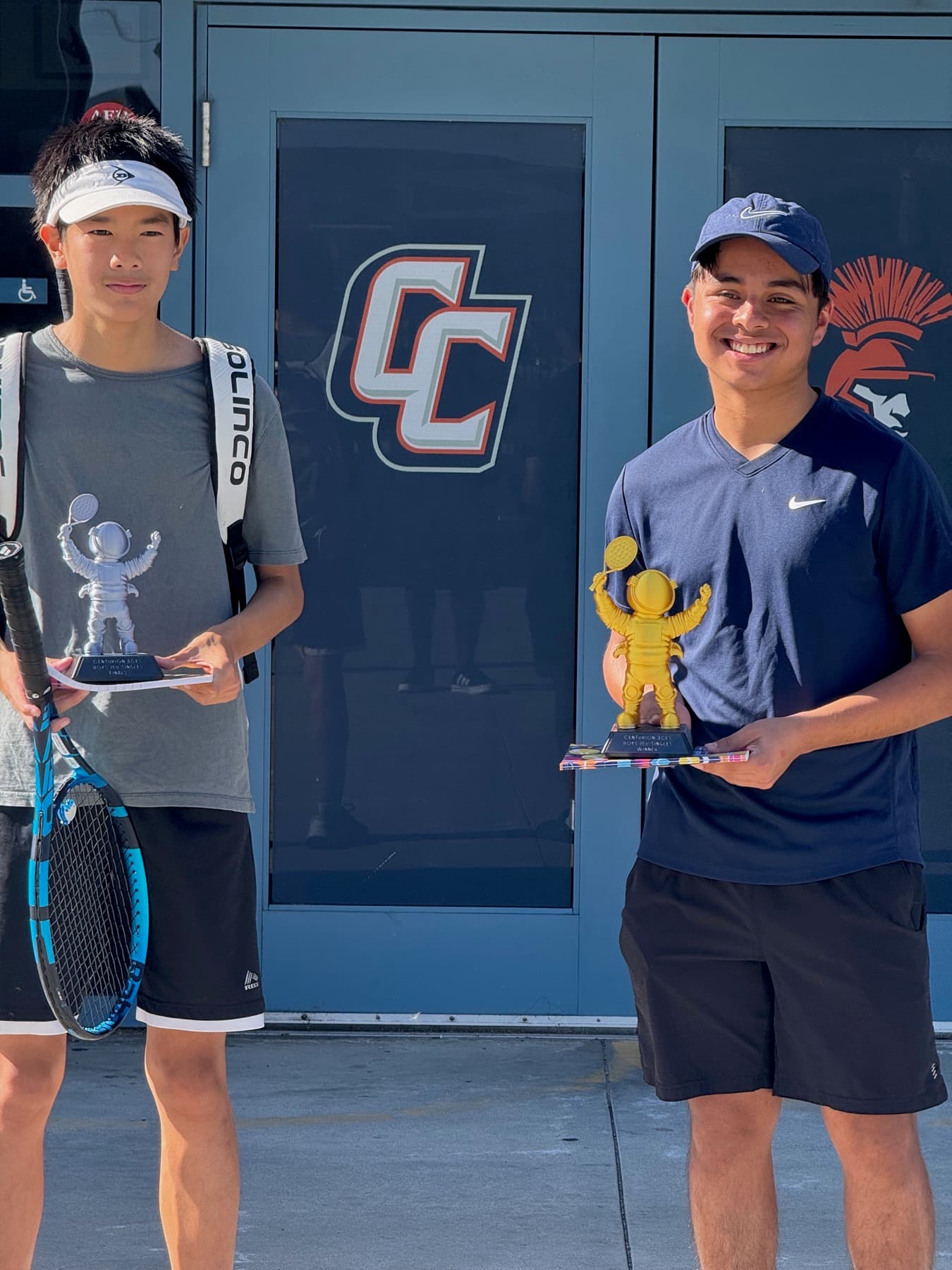 Two players holding tennis trophies